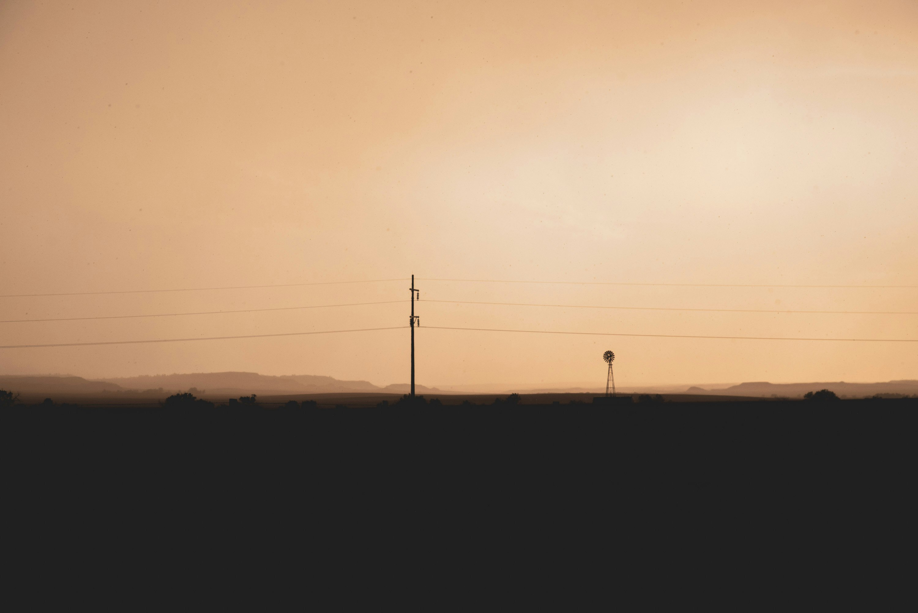 silhouette of electric post during sunset